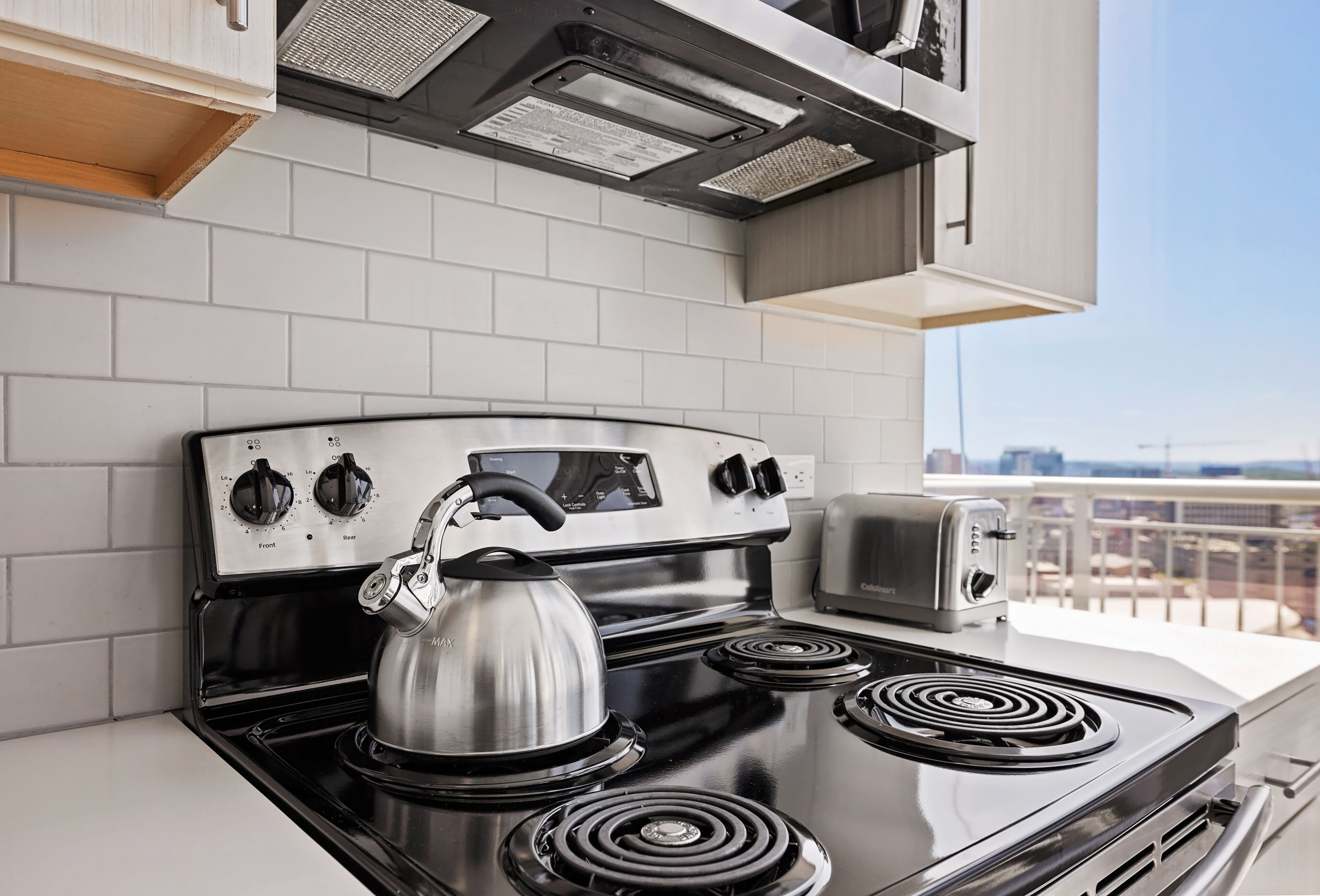 A modern kitchen with a stainless steel stove, a kettle, and a toaster.
