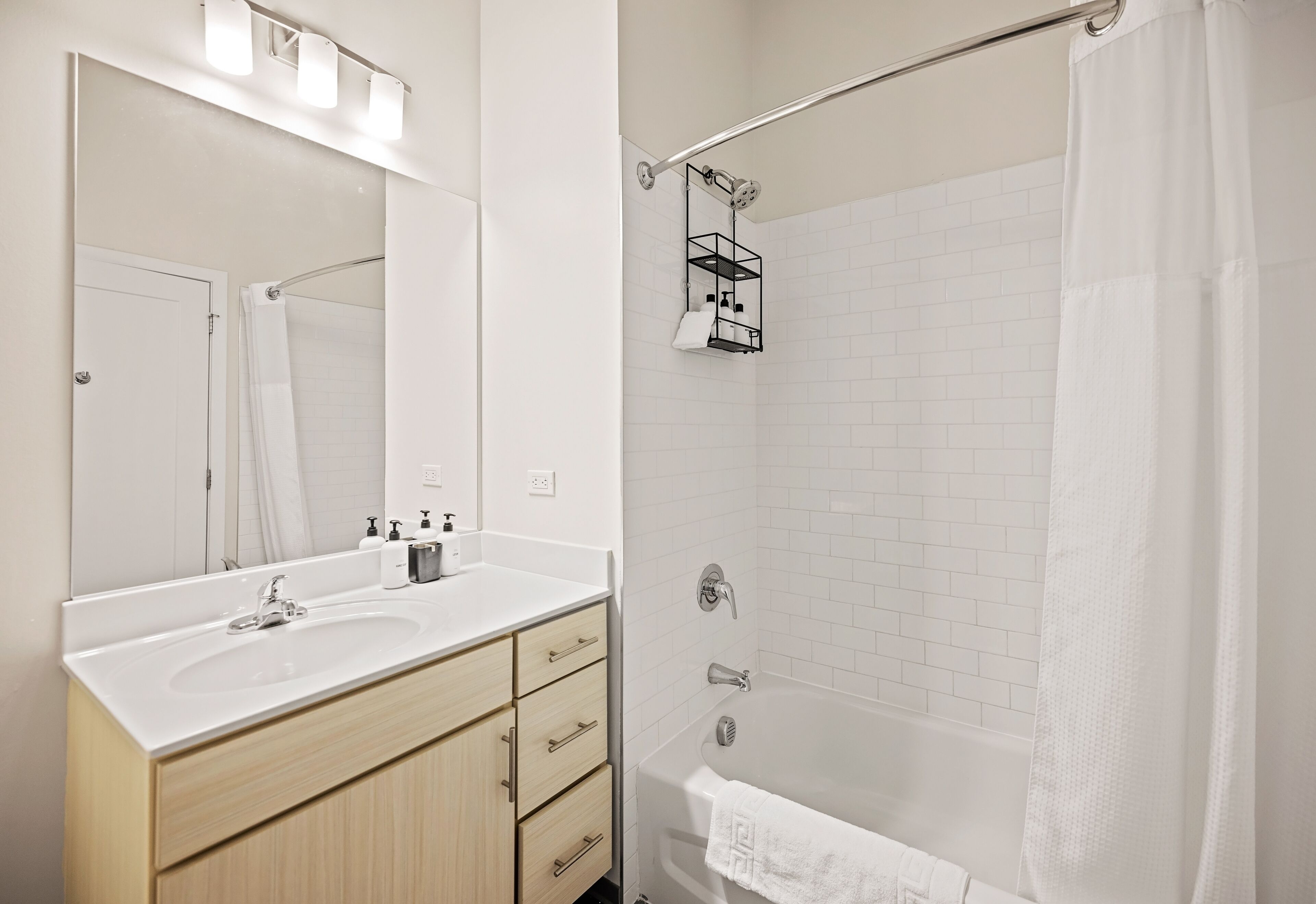 A modern bathroom with a white sink, vanity, and bathtub.