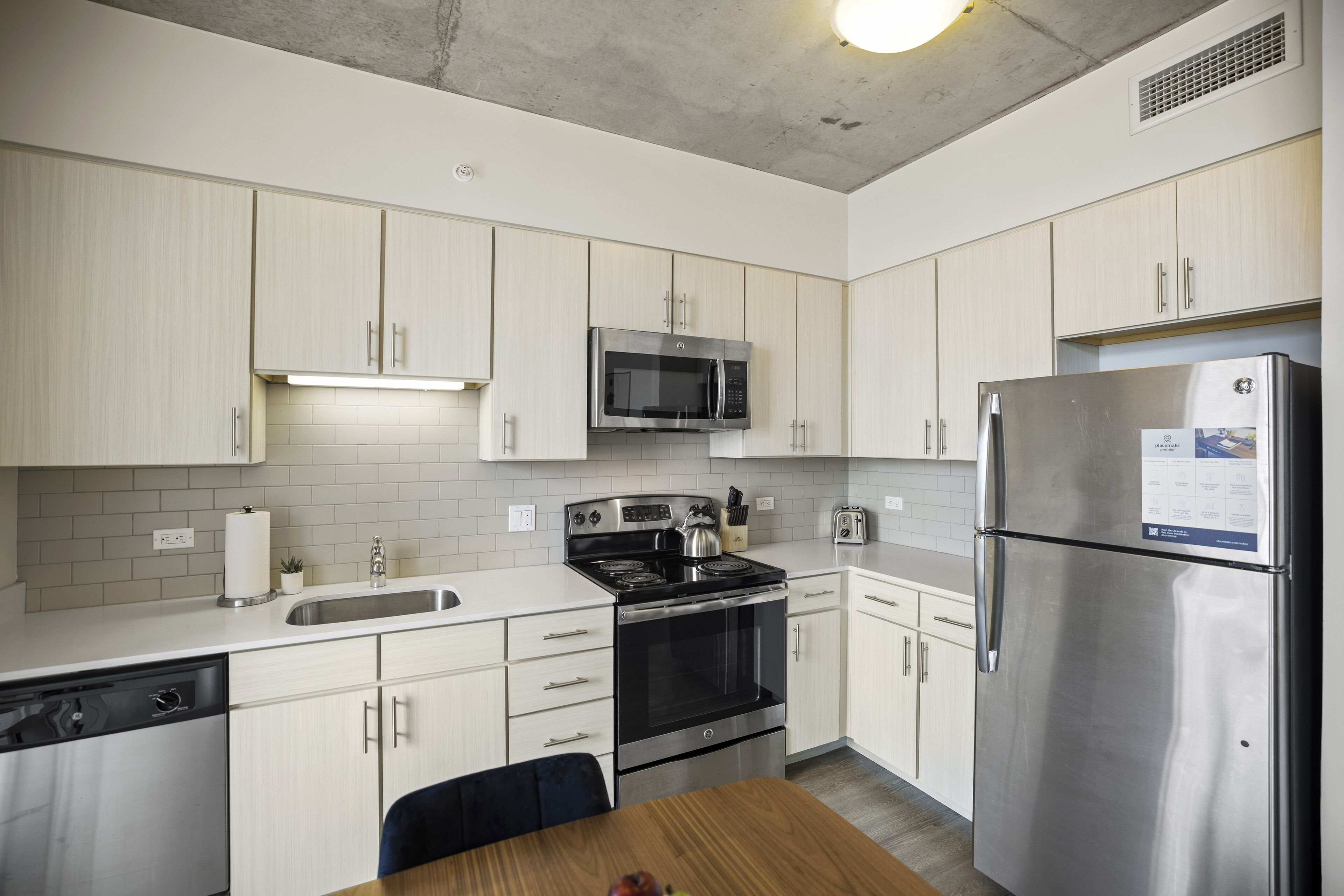 Una cocina moderna con armarios blancos, electrodomésticos de acero inoxidable y una mesa de comedor de madera.