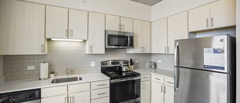 Una cocina moderna con armarios blancos, electrodomésticos de acero inoxidable y una mesa de comedor de madera.