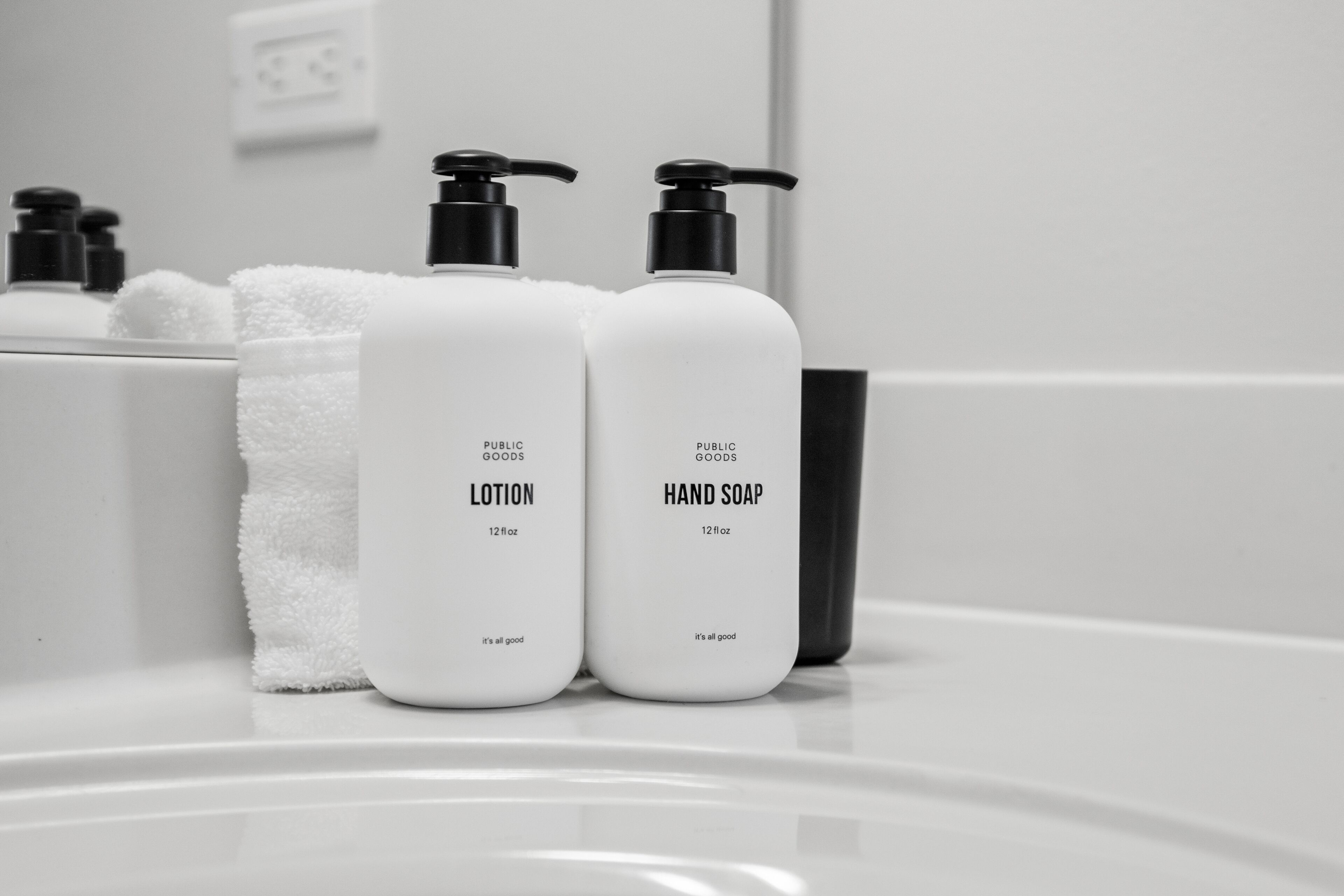 Two bottles of lotion and hand soap on a bathroom counter.