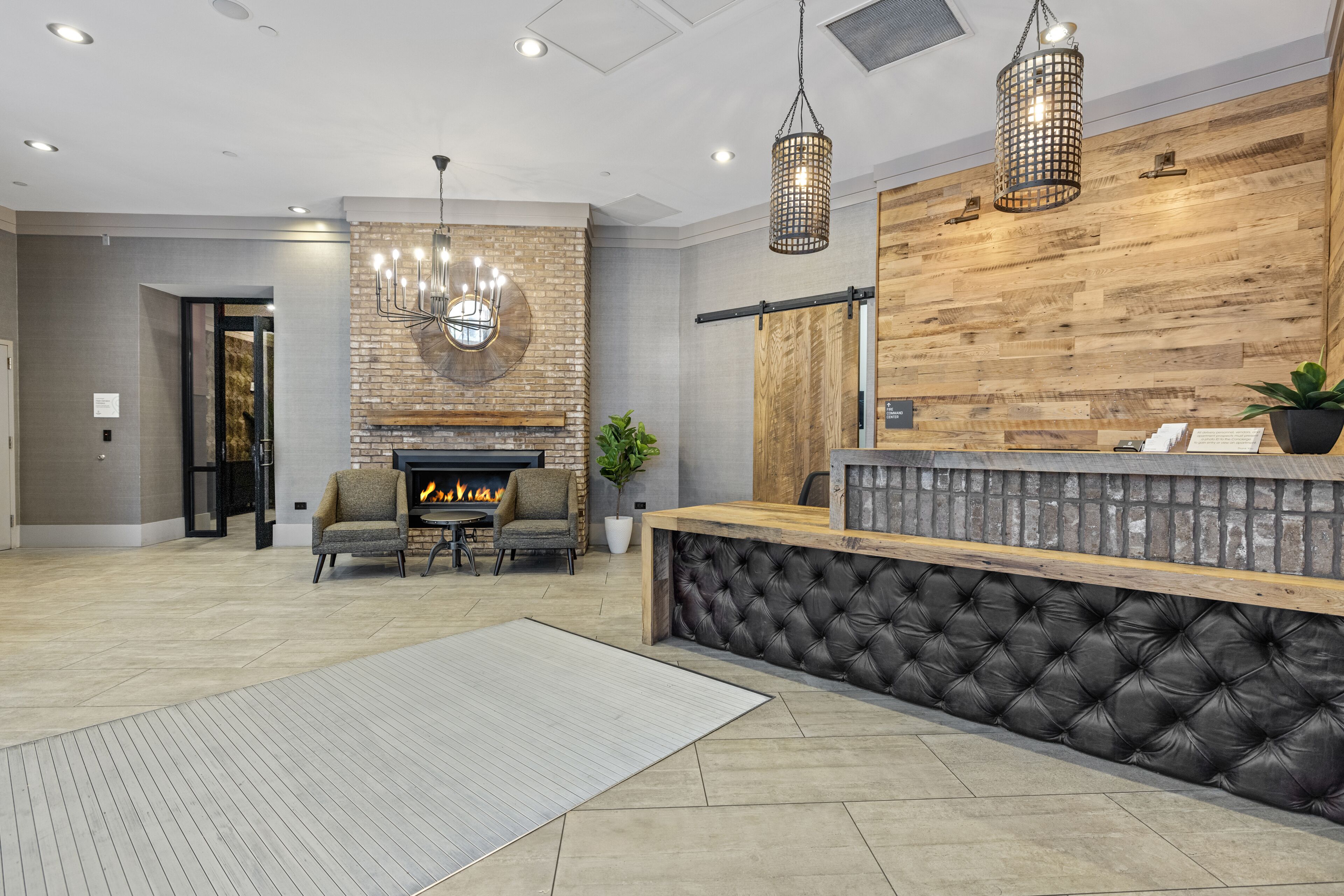 Una hall moderna con camino, area salotto e reception con bancone in legno e schienale imbottito nero.