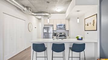 A modern kitchen with a central island, stainless steel appliances, and bar stools.