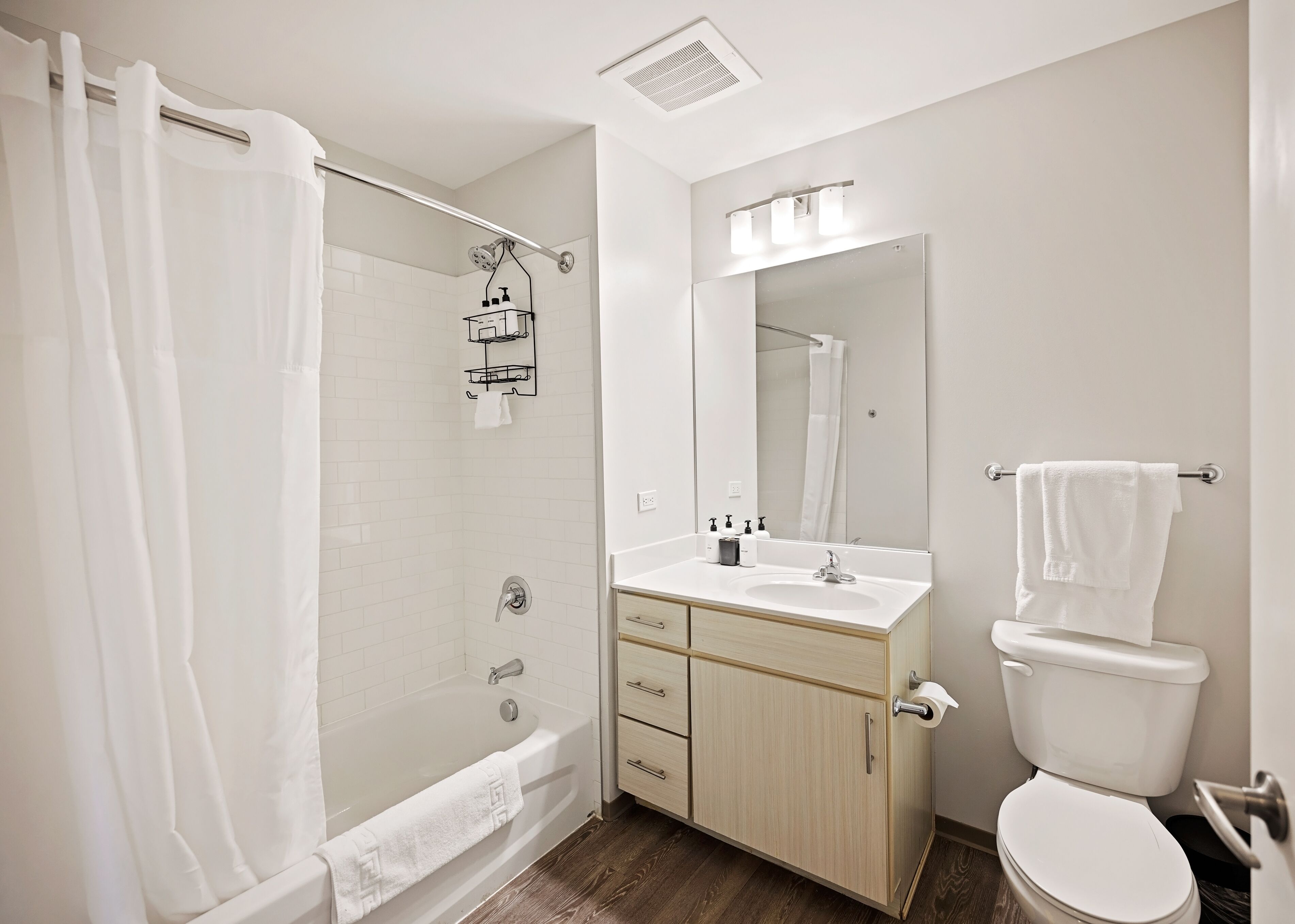 Een moderne badkamer met een inloopdouche, toilet en een wastafel met spiegel erboven.