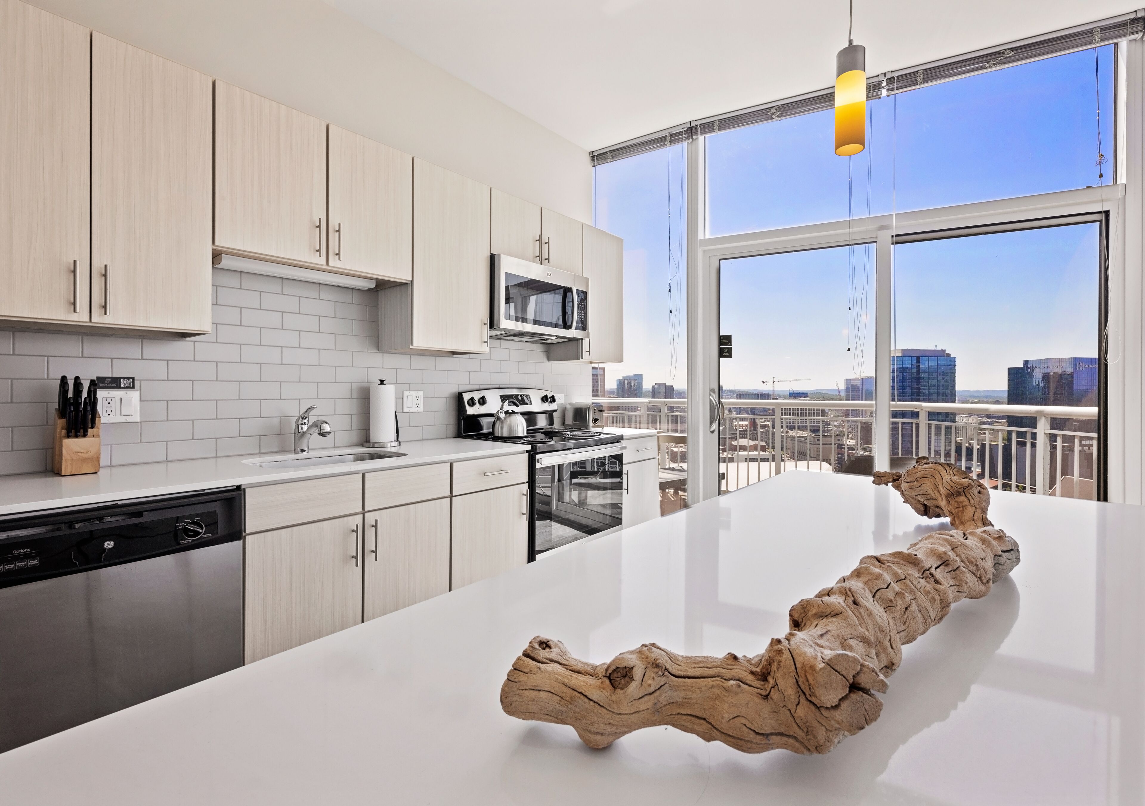 A modern kitchen with white cabinetry, a large island, and a city view through the windows.