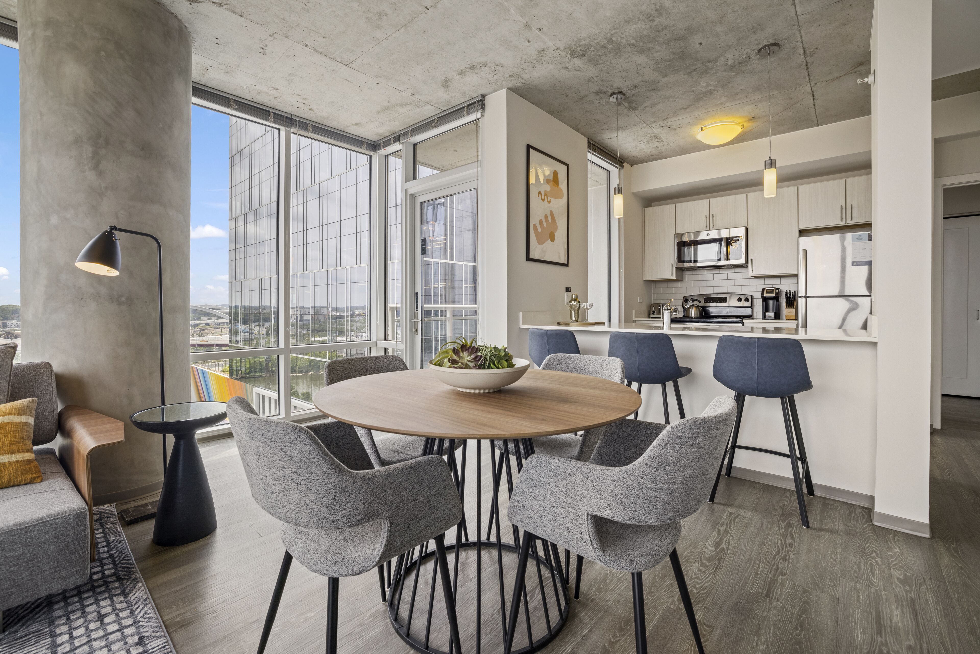 Een modern appartement met een eethoek, keuken en grote ramen met uitzicht over de stad.