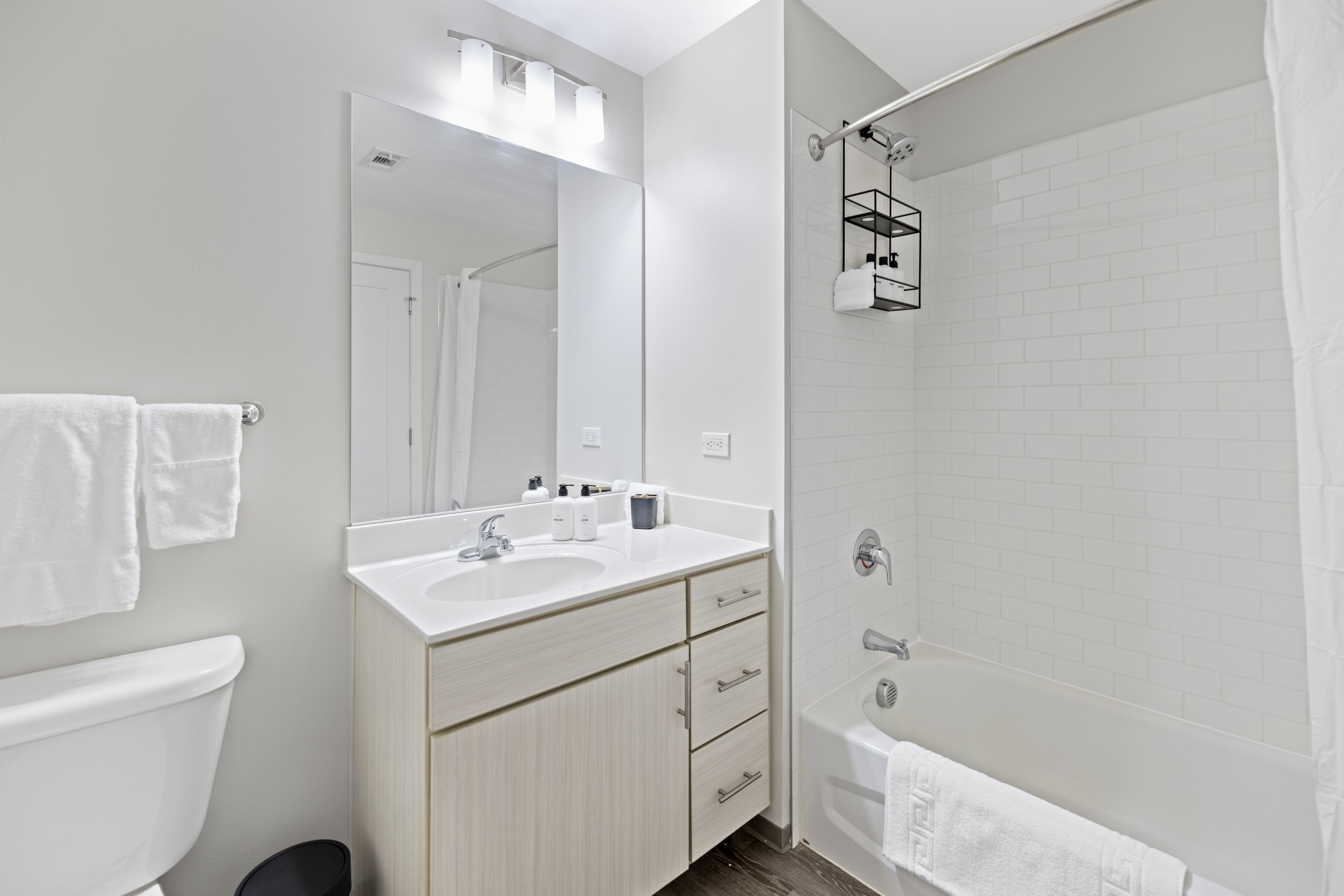 Un baño moderno con inodoro, lavamanos, espejo y ducha.