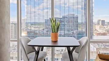 A modern office space with a large window, a table with chairs, and a potted plant.