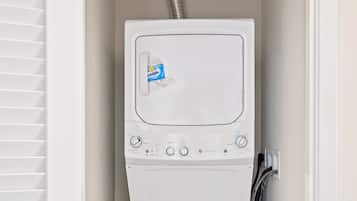 A compact, white front-loading washer and dryer unit with a control panel, a vent hose, and a door with a window.