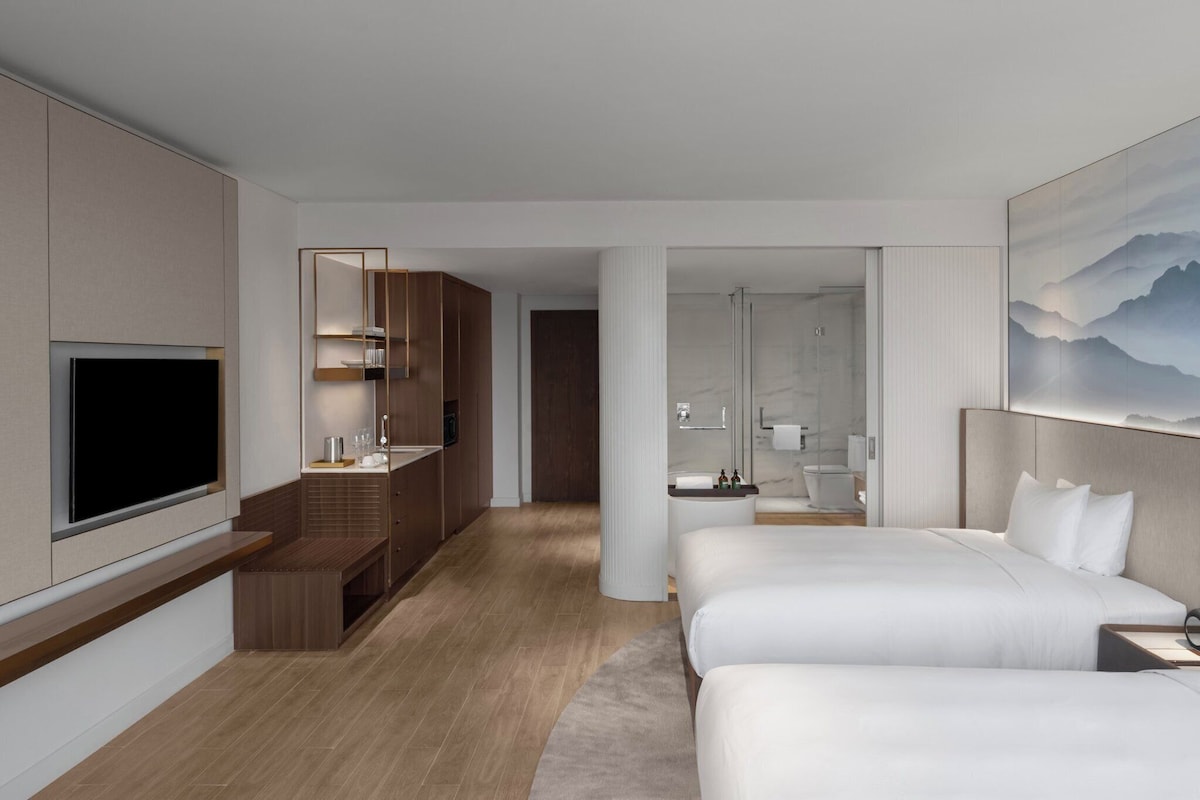 A hotel room with a TV, a bed, a desk, and a bathroom.