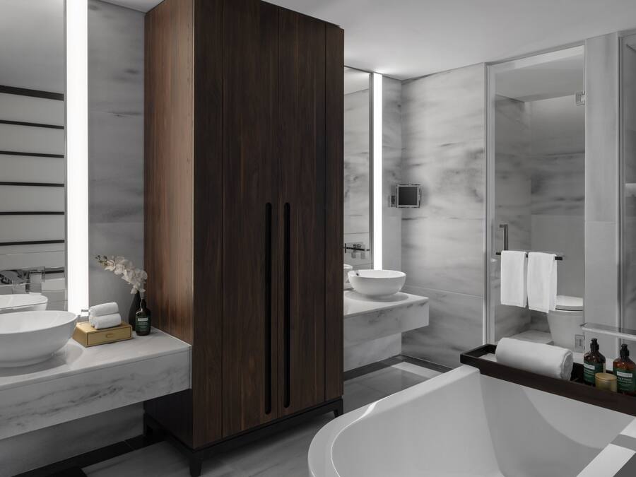 A modern bathroom with a large bathtub, two sinks, and a wooden wardrobe.