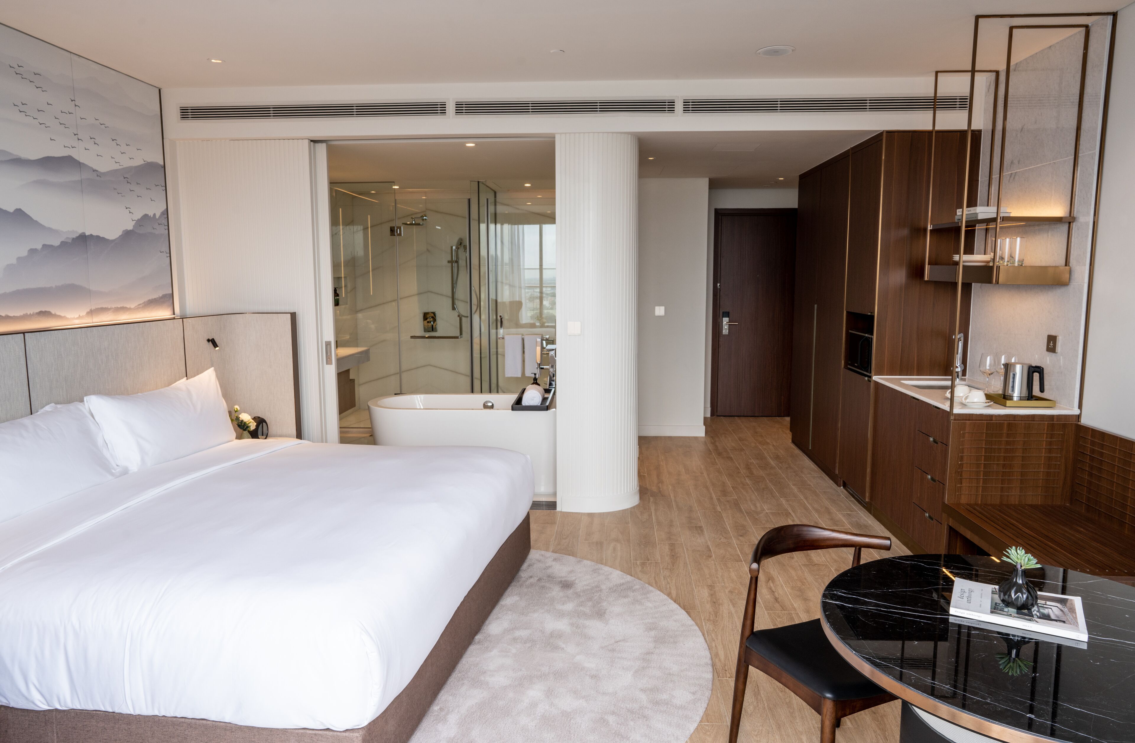 Ein Hotelzimmer mit einem großen Bett, einem Schreibtisch mit Stuhl, einem Badezimmer mit Duschkabine und Bergblick.