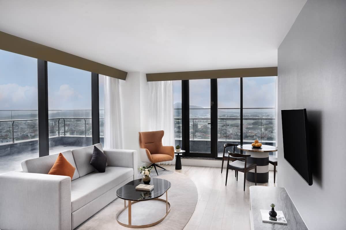 A modern living room with a sofa, armchair, coffee table, and dining area.