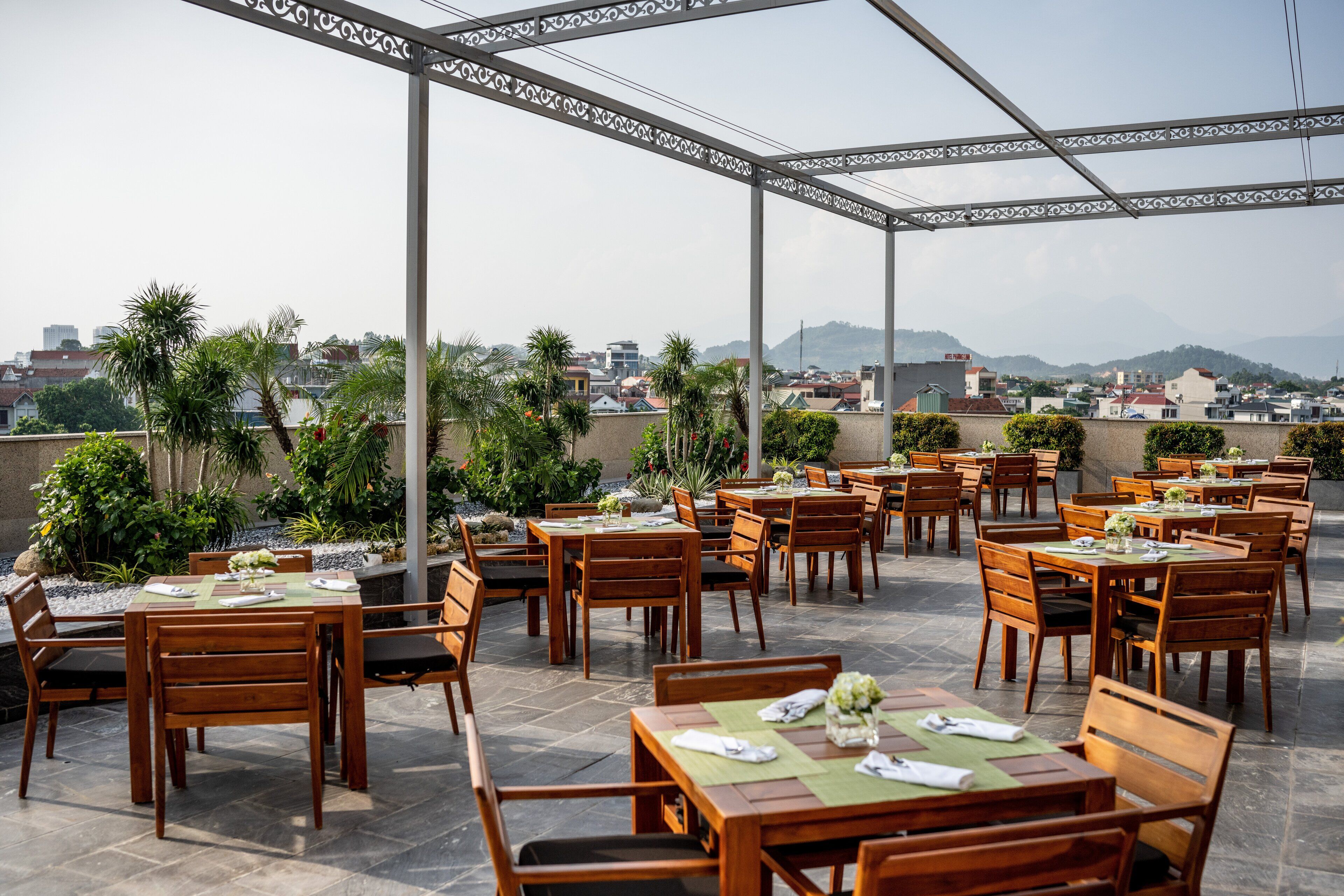 An outdoor dining area with tables and chairs, surrounded by a decorative metal pergola.