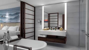 A modern bathroom with a large mirror, a bathtub, and a vanity with toiletries.