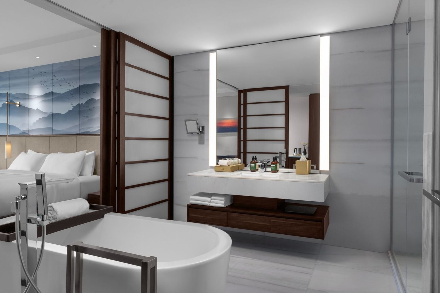 A modern bathroom with a large mirror, a bathtub, and a vanity with toiletries.