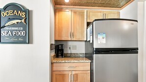 A kitchen with wooden cabinets, a stainless steel refrigerator, and a coffee maker.
