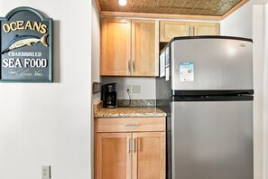 Una cocina con armarios de madera, un refrigerador de acero inoxidable y una cafetera.
