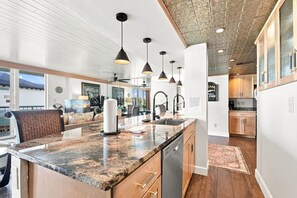 A modern kitchen with a granite countertop, pendant lighting, and a view to the outside. - ⭐Gulf & Sound View-Corner Wraparaound Balcony-Pool-Tennis-2BR Tristan Towers 1B⭐ (Pensacola Beach)
