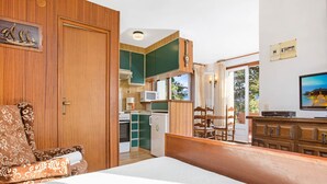 A room with a bed, a wooden chair, a dining table with chairs, a kitchen area with a microwave, and a television. - 1BENET EST - House divided into 3 totally independent apartments with shared pool just 1 km from the beach of Calella de Palafrugell (Calella de Palafrugell)