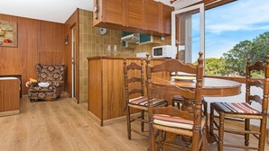 A wooden kitchen with a dining area, a clock, and a view of greenery outside. - 1BENET EST - House divided into 3 totally independent apartments with shared pool just 1 km from the beach of Calella de Palafrugell (Calella de Palafrugell)