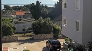 A residential building with a clear view of the surrounding landscape, including trees and distant mountains. - Apartment Ugljanski Gusari (Preko)