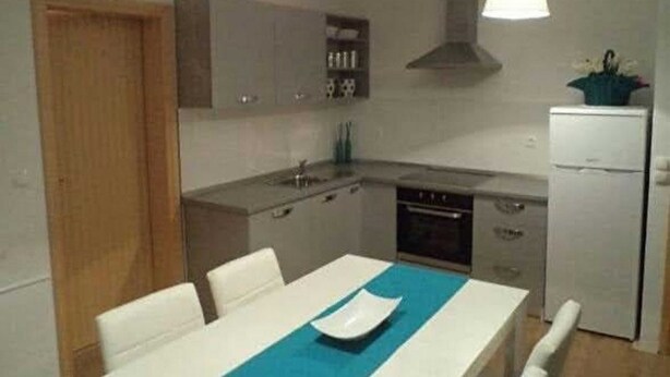 A compact kitchen with a dining area, a built-in oven, and a refrigerator. - Apartment Ugljanski Gusari (Preko)