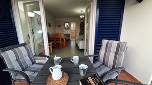 Un comedor con una mesa dispuesta para cuatro personas, con cojines a rayas y un mantel tejido.