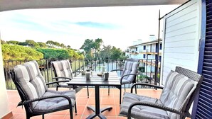 Un balcón con una mesa y sillas, con vistas a una zona residencial con árboles y edificios.