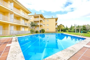 A swimming pool with a tiled deck, a multi-story building with balconies, and a well-maintained lawn. - 1CEN A1 -Basic  apartment with communal garden and pool, only 800m from the  beach of Llafranc (Llafranc)