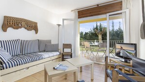 Una sala de estar acogedora con un sofá a rayas, una mesita y un televisor en un balcón con vistas panorámicas.