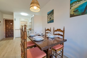 A dining area with a wooden table set for four, surrounded by wooden chairs with red cushions.