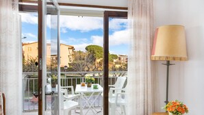 A balcony with a table and chairs, a potted plant, and a lamp.