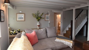 En stue med sofa, sofabord og trappe.