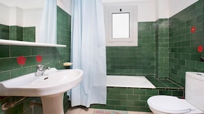 A bathroom with green tiles, a white sink, a bathtub, and a toilet. - 1ARCH1 Basic 2 bedroom apartment close to the lovely beach of Pals. (Pals)