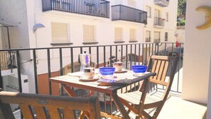 A balcony with a table set for two, featuring a coffee maker, bowls, and a magazine.