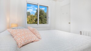 Un dormitorio con una cama grande, dos ventanas, un radiador y una puerta.