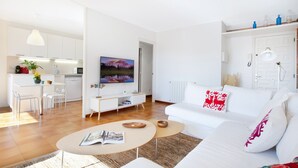 Una sala de estar moderna con un sofá blanco, una mesa de centro y un comedor con una mesa y sillas blancas.