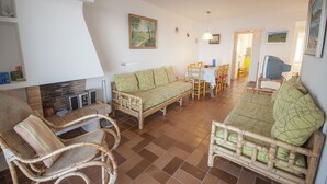 A living room with a sofa, chairs, a dining table, and a TV. - 1MED 17 - Basic apartment in front of the beach of Pals and 100m from the  town centre. (Pals)