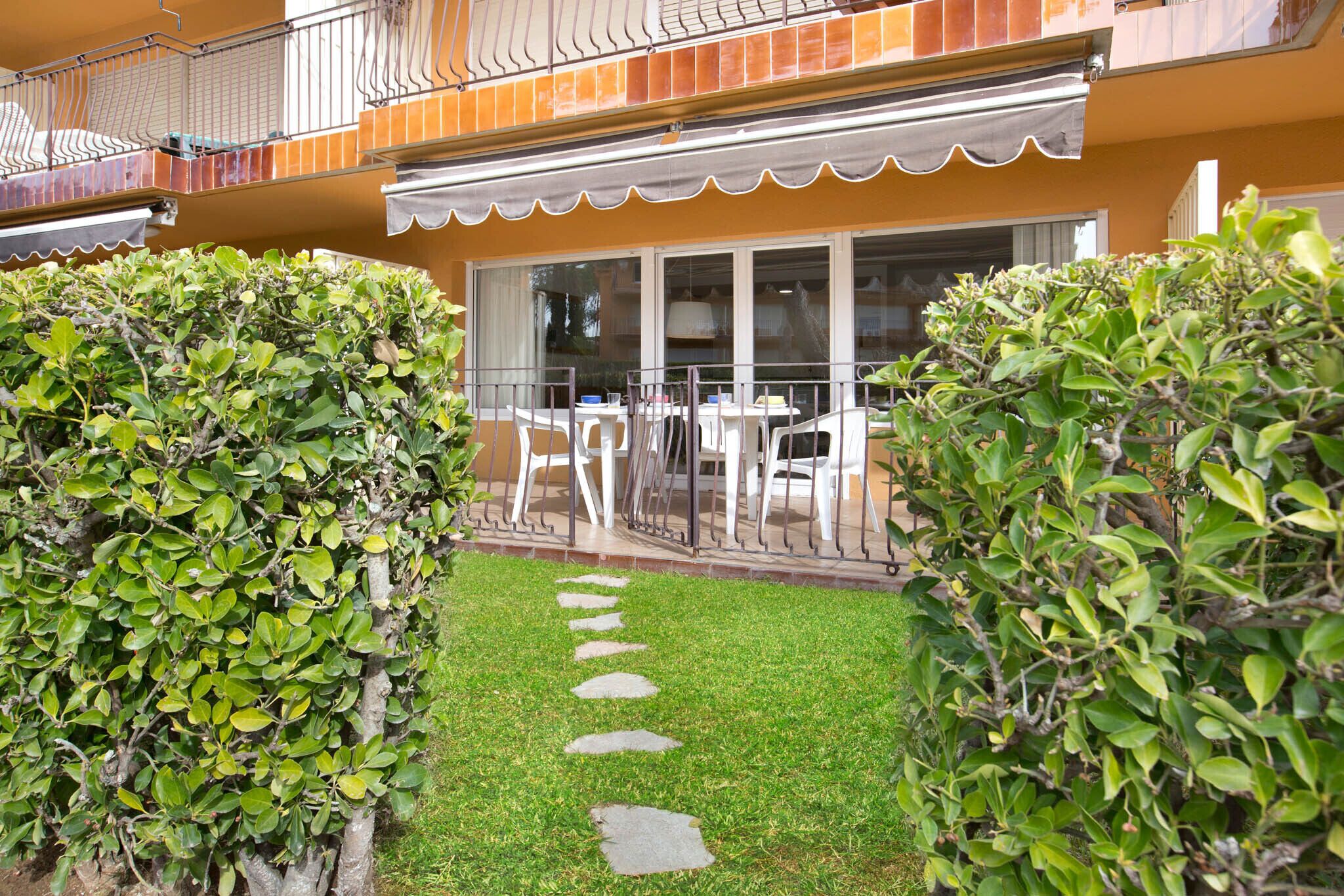 Un patio con sendero empedrado, mobiliario exterior blanco y un balcón con barandilla.
