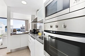 A modern kitchen with stainless steel appliances, a built-in oven, and a window overlooking a scenic view.