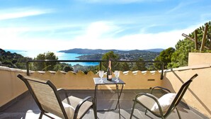 Un balcón con dos sillas y una mesa, con vista a un paisaje costero.