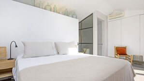 Un dormitorio moderno con una cama grande, una silla y un armario.
