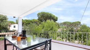 A balcony with a glass table and chairs, a white railing, and a view of trees and buildings in the background. - 1PAN 01 - Basic house divided into 3 independent apartments located a few meters from the beautiful beach of Llafranc (Llafranc)