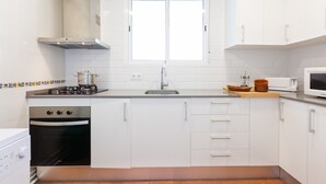 A modern kitchen with white cabinets, a stainless steel stove, a microwave, and a window above the sink. - 1PAN 01 - Basic house divided into 3 independent apartments located a few meters from the beautiful beach of Llafranc (Llafranc)