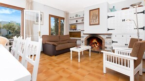 A living room with a sofa, chairs, a coffee table, a fireplace, and a view through a glass door. - 1BENETPL - House divided into 3 totally independent apartments with shared pool just 1 km from the beach of Calella de Palafrugell (Calella de Palafrugell)