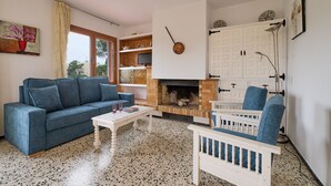 A living room with a blue sofa, white coffee table, and a fireplace. - 1BENET 1 - House divided into 3 totally independent apartments with shared pool just 1 km from the beach of Calella de Palafrugell (Calella de Palafrugell)