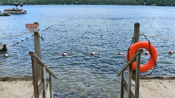 A wooden dock with a warning sign, a lifebuoy, and a boat in the background. - Quiet townhome between Canandaigua and Naples in the Finger Lakes (Canandaigua)