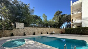 A swimming pool with a stone wall and trees in the background.
