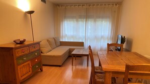 Una sala acogedora con una mesa de comedor de madera, un sofá y un aparador de madera.